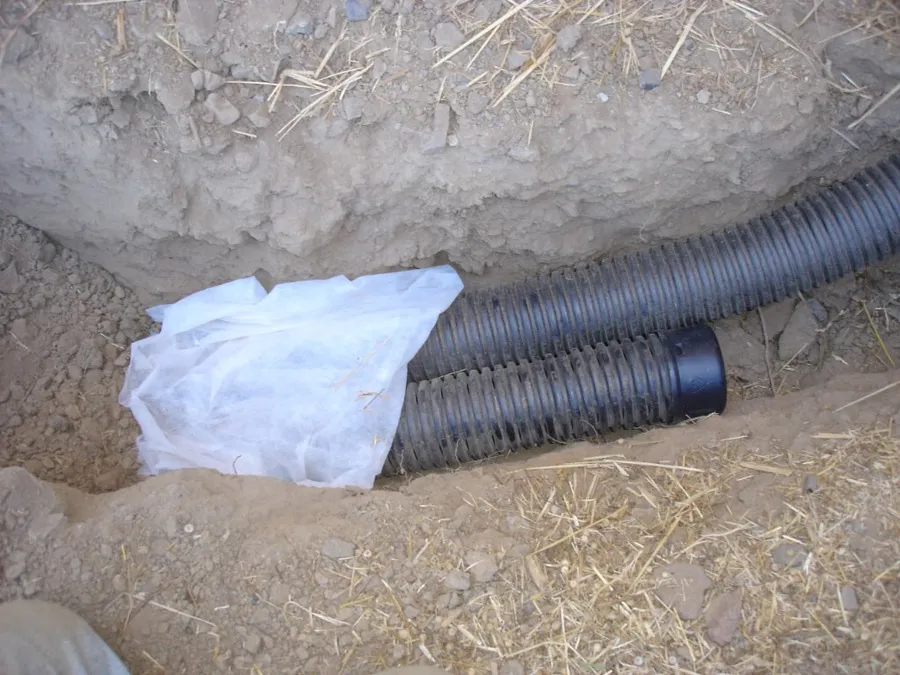 Perforated drain pipe and geotextile filter fabric being installed in Nashville drainage trench