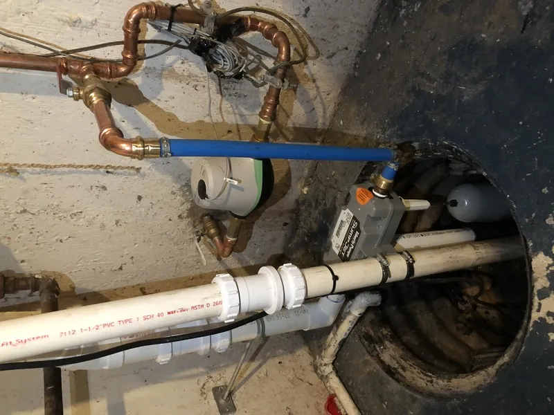 Newly installed residential sump pump in basement pit with PVC discharge line
